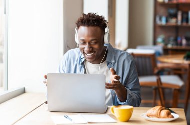 Haberleşme konsepti. Milenyum boyunca kulaklıklı, Afro-Amerikan bir adamın internetteki internet bilgisayarından iletişim kurduğu mutlu siyahi adam.