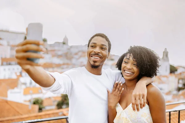 Happy young african american guy hugging woman, taking selfie, enjoy date and travel in city outdoor. App for video call, photo for social networks, vacation together and romance, relationship