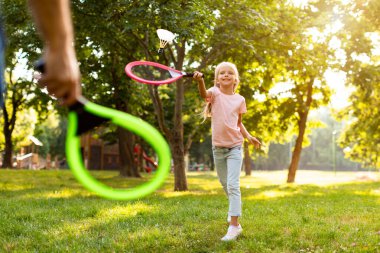 Mutlu bir baba-kız ailesi çayırda ya da parkta badminton oynayarak hafta sonu ve zamanın tadını çıkarıyor. Aile, çocuklar ve doğa konsepti