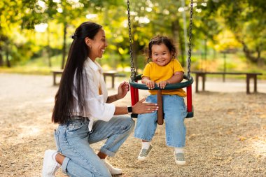 Çocuk bakımı eğlencesi. Asyalı Milenyum Annesi 'nin dışarıda kız çocuğunu sallamasına sevindim. Anneciğinin haftasonu şehir parkında şirin bebeğiyle oynaşması ve yakınlaşması.