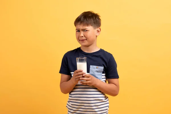 子供の概念のためのラクトース不耐性 イエロースタジオの背景 コピースペースに隔離された 彼の手と笑顔で牛乳を保持するカジュアルな衣装で不幸な子供の少年 — ストック写真