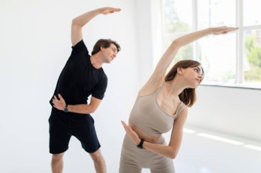 Spor giyimli ciddi beyaz erkek ve bayan spor giyim kuşamında birlikte antrenman yapmaktan, spor salonunda ya da iç mekanda ellerinizi esnetme egzersizlerinden hoşlanırlar. Evde spor, sağlık, spor, ısınma ve ilişki