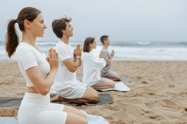 青少年在海滩上练习瑜伽和冥想 双手紧握坐在垫子上 在海滩上享受户外训练 自由自在的空间 — 图库照片