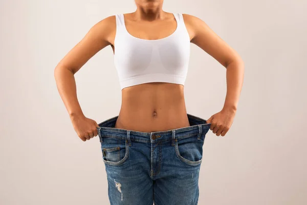 거대한 바지를 여성의 그녀의 오래된 청바지를 보여주는 다이어트의 결과를 보여주는 — 스톡 사진