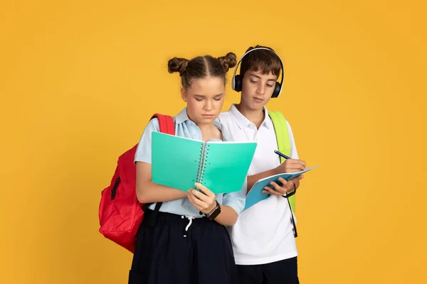 严重的高加索少年男女学生背包学习 准备考试孤立的橙色工作室背景 在学校教育中作弊 做广告和提供工作 — 图库照片