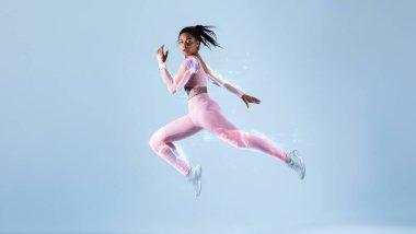 Modern gelecekçi spor teknolojileri konseptiyle eğitim. Spor giyinen, atlayan ya da koşan, neon mavisi stüdyo arka planı üzerinde egzersiz yapan, serbest alan, tam boy. Enerji ve spor