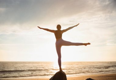 Beyaz kadın profesyonel atlet yoga yapıyor, nefes egzersizlerini seviyor, deniz sahilinde dengeyi sağlıyor. Sabah sporu, tek başına spor, sağlık ve aktif yaşam tarzı.