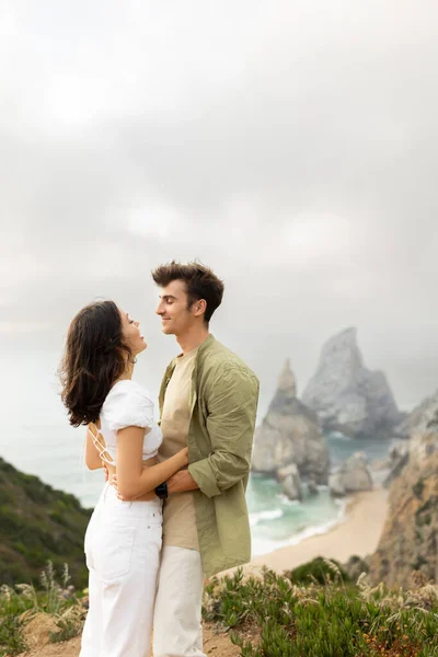 ロマンチックなデートを持っている恋の若いカップル 抱擁し お互いを見て 海岸の美しい景色と海岸線に立って 垂直ショット コピースペース — ストック写真