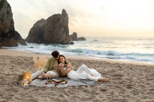 浪漫的夫妇野餐 坐在毯子上拥抱 在海滩上享受约会 庆祝浪漫的时刻 订婚或结婚周年纪念日 复制空间 — 图库照片