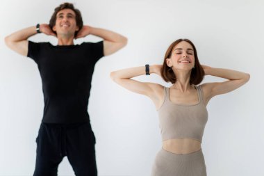 Spor giyimli genç beyaz adam ve bayan birlikte antrenman yapmaktan zevk alıyor, elleri beyaz arka planda. Evde spor, sağlık, spor ısınma ve ilişkiler.