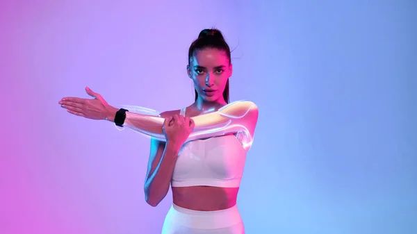 Sports and technology concept. Sports tech. Health care technology. Fit lady in white fitwear stretching arms wearing smart fitness watch exercising on neon background. Sport motivation, panorama