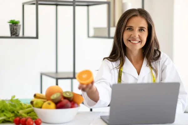 Masada Beyaz Önlüklü Organik Meyveli Bir Laptopla Gülümseyen Kafkas Kadın — Stok fotoğraf