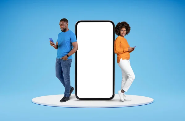 与移动应用程序的概念约会 千年快乐的黑人男女休闲地站在平台上 手持大手机 复制广告空间 蓝色背景隔离 — 图库照片