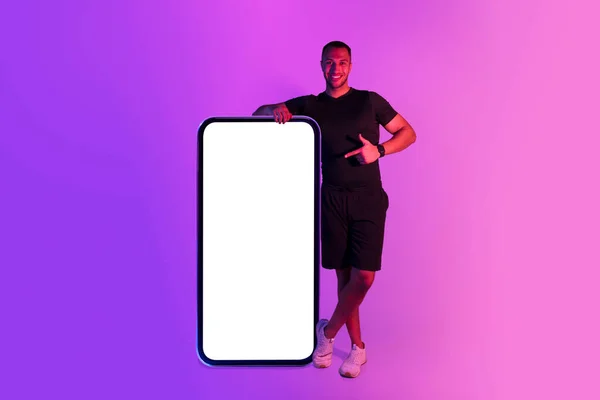 Мускулистый Атлетичный Африканский Американец Опирающийся Огромный Телефон Указывающий Пустой Экран — стоковое фото