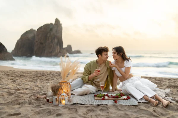海の景色を望む砂浜でピクニックをしているロマンチックな若いカップル ワインを飲んだり 果物を食べたり 海岸線で夜を楽しんだり 自由なスペース — ストック写真