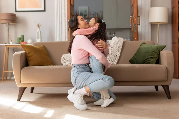Mother and Daughter Moments. Affectionate Asian Mom Hugging Her Darling Little Child Girl, Expressing Love and Affection in the Comfort of Their Home. Joyful Bond of Motherhood Concept