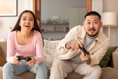 Çift Bağlanma ve Kaliteli Zaman. Neşeli Japon koca ve karısı video oyunları oynuyorlar, dostça bir rekabete giriyorlar evde koltukta otururken eğleniyorlar. Ön Görünüm