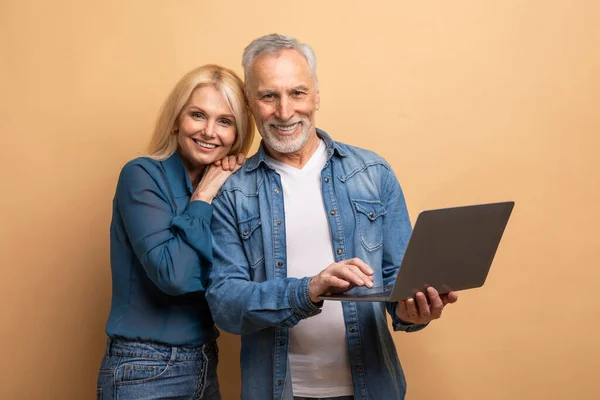 愛する陽気で魅力的な高齢者の配偶者は幸せに結婚した夫と妻ベージュの背景にPcのコンピュータのラップトップを使用して オンライン素敵なムービーを見て ウェブサーフィン インターネット上でスクロール — ストック写真