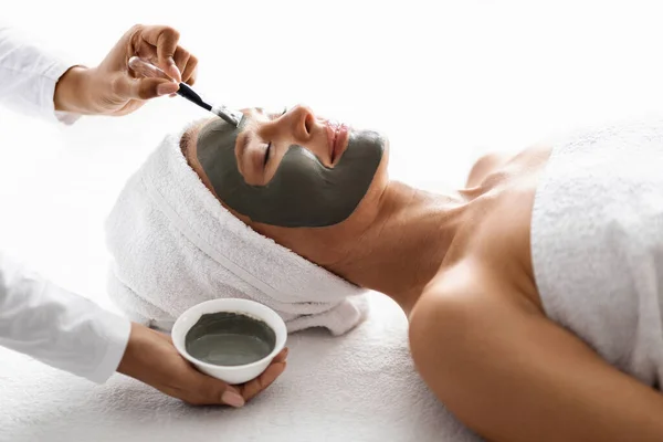 Pflegekonzept Kosmetikerin Trägt Feuchtigkeitsspendende Gesichtsmaske Auf Schöne Frau Mittleren Alters — Stockfoto