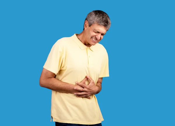 腹部的疼痛 成熟男子患有胃痛 腹部痉挛疼痛 在蓝色背景下触胃 演播室拍摄 健康问题概念 — 图库照片