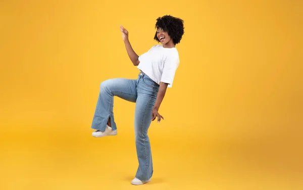 快乐的年轻黑人卷曲女子独自穿着白色T恤跳舞 在橙色背景 演播室 全身上下都有乐趣 业余时间的娱乐 广告和提供 人类的情感 — 图库照片