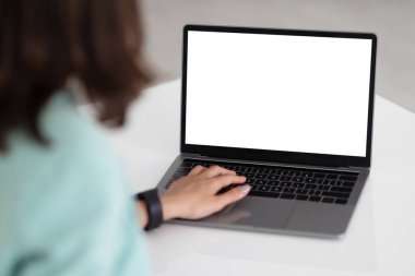 Masada dizüstü bilgisayarında ofis içi boş ekranla yazı yazan beyaz takım elbiseli genç bir iş kadını, kesilmiş. İş görüşmesi kumandası, video görüşmesi, iş ve teknoloji, web sitesi ve uygulama