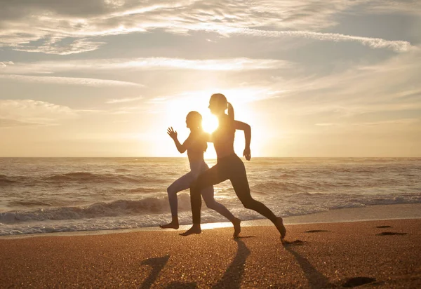 Positive energy millennial caucasian twins sisters women running, enjoy workout at sea beach, sun flare. Morning cardio workout, cardio fitness, sports together outdoor, health care