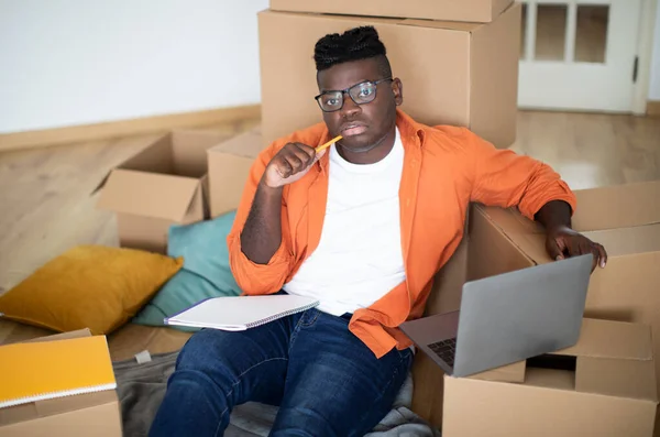 Pensive Black Young Man Sitting Cardboard Boxes Using Laptop Millennial — Stock Photo, Image