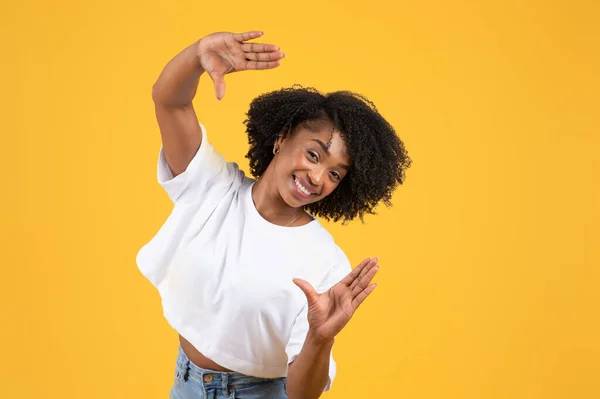 快乐的年轻黑人卷曲女士穿着白色的T恤制作框架标志 镜头与手隔离在橙色背景 工作室 创意照片姿态 生活方式 广告和服务以及乐趣 — 图库照片