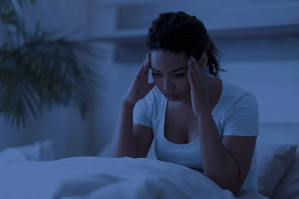 不眠之夜的黑人妇女独自坐在床上 触摸着她的头 沉思的非洲裔美国妇女患有失眠 有沉重的思想或严重的偏头痛 感到冷漠和沮丧 — 图库照片