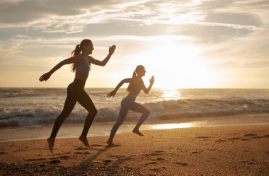 Gülümseyen bin yıllık Kafkas ikiz kız kardeşler koşan kadınlar, deniz sahilinde çalışmanın tadını çıkarıyorlar. Sabah kardiyo çalışması, yarışma, birlikte spor, sağlık ve aktif yaşam tarzı.