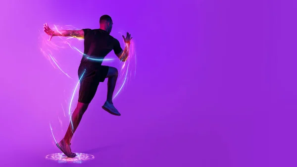 Digital sport, sports technology concept. Motivated black sportsman exercising on purple background in neon light, running or jumping towards copy space, hologram over athlete body, panorama