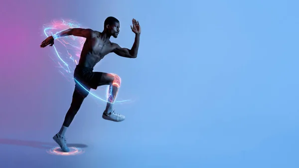 Full length portrait of focused young black man with bare torso running fast in neon lighting, panorama, copy space. Side view of motivated African American sportsman jogging, digital sport concept