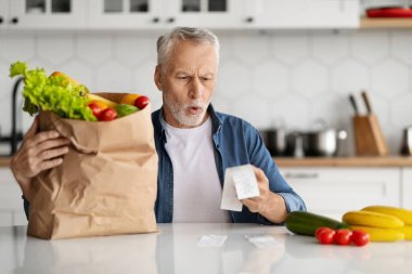Yemek için Fiyatlar. Süpermarketten alışveriş yaptıktan sonra markette bakkal faturalarını kontrol eden yaşlı bir adamın portresi, Hayal kırıklığına uğramış yaşlı bir beyefendinin açık ağızla kitap okuması,