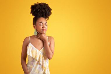 Mutsuz bin yıllık siyahi kadın, acı, grip ve soğuktan muzdarip, turuncu arka planda, stüdyoda elini gırtlağına bastırıyor. Boğaz ağrısı, sağlık sorunları, insan duyguları, hastalık belirtileri