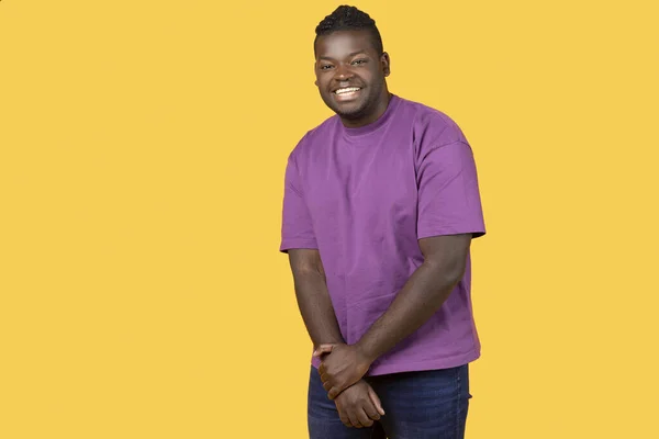 害羞的非洲裔美国年轻人面带微笑地看着相机 手牵着手 装腔作势地穿上休闲的紫色T恤 站在黄色的背景上 带着自由自在的空间拍摄 — 图库照片