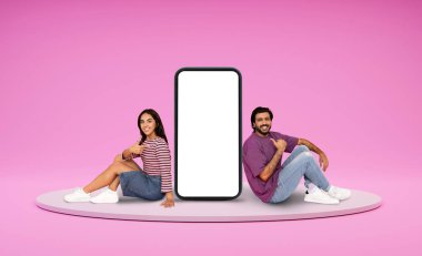 Rahat, mutlu, mutlu, binlerce yıllık Hintli erkek ve kadın aşıklar platformda beyaz ekranlı, kocaman bir telefonun yanında takılıyorlar. Güzel bir flört uygulaması, pembe arka plan, boş bir alan gösteriyorlar.