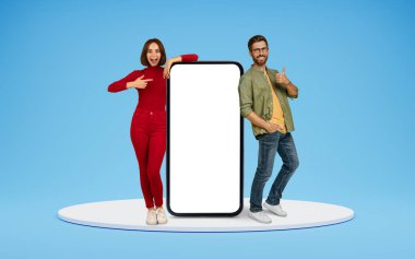 Alışveriş gezici uygulama konsepti. Mutlu milenyum erkek ve kadın platfotm üzerinde beyaz ekranlı büyük bir telefonla, reklam için kopya alanı, mavi arka planda izole edilmiş.