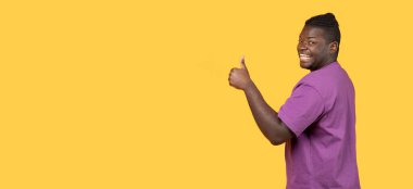 Harika seçim. Afro-Amerikalı olumlu bir genç adam sarı arka planda kameraya işaret ediyor. Mutlu bir milenyum adamı gibi bir şey öneriyor. Panorama, boşluğu kopyala