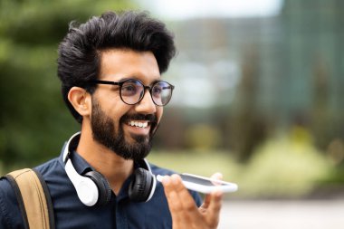 İletişim. Gözlüklü, kablosuz kulaklık takan ve omzuna çanta takmış, sevgilisine sesli mesaj kaydeden ya da telefonla yıpranmış sokakta yürüyen, fotokopi çeken neşeli Hintli genç adam.