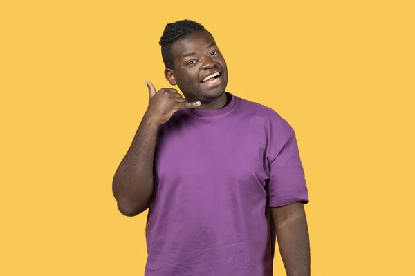 快乐的非洲裔美国人给我打手势 手牵手 像手机一样靠近耳朵 在黄色的背景上摆出姿势 穿着紫色T恤 联系方式 电话号码和通讯概念 — 图库照片