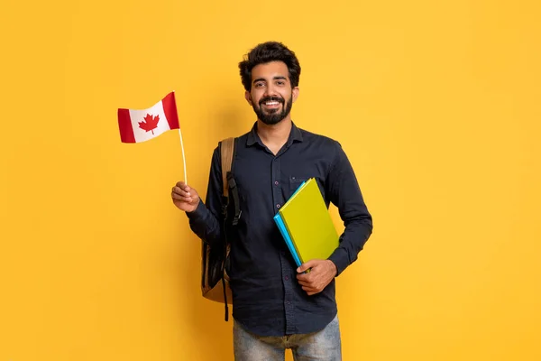 Usmívající Indiánský Muž Kanadskou Vlajkou Sešity Rukou Držení Žlutém Pozadí — Stock fotografie