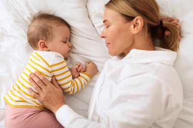 Rüyalarda kaynaşmak. Anne, sevimli küçük kızıyla yatıyor. Kadın, çocuğu kucaklıyor. Yatakta gözleri kapalı yatıyor.