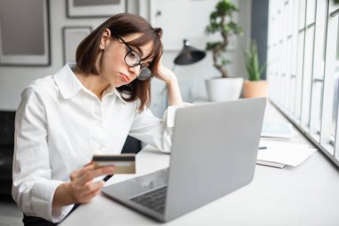 Çevrimiçi alışveriş sorunları. Diz üstü bilgisayar ve kredi kartı kullanan hoşnutsuz iş kadını internet ödemesinde sorun yaşıyor. Bankacılık hizmeti sorunu kavramı