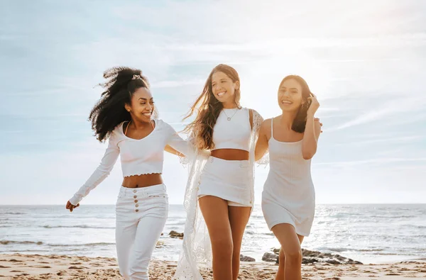Three diverse ladies embracing and laughing, walking at the beach, enjoying bachelorette party celebration outdoors. Best friends having fun and enjoying their holiday