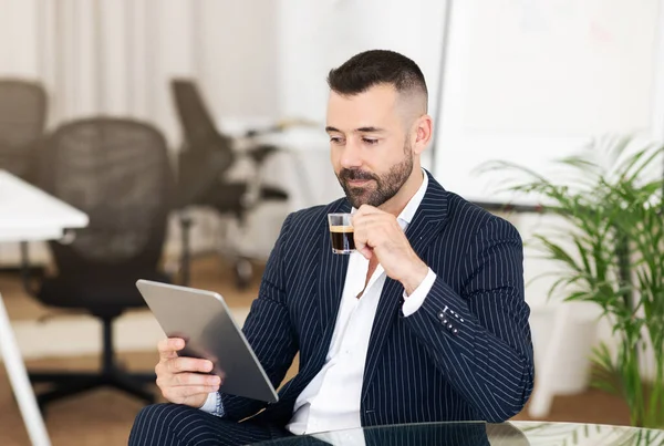 真剣な自信を持って警戒心のある成熟した男は コーヒーを飲みながら コワーキングオフィスのインテリアでビジネスのためのタブレットでチャットします スタートアップ ビジネスマン アプリ ガジェット ライフスタイルの企画 — ストック写真