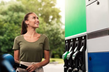 En iyi yakıt fiyatı. Neşeli Sürücü Kadın Biyolojik yakıtla otomobil deposunu dolduruyor, Modern Benzin İstasyonunda silah başlığının yanında duruyor. Kolay Araç Yakıt Hizmeti Konsepti