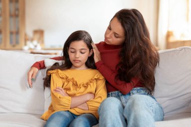 Çocuk Depresyonu Konusu. Destekleyici Arap anne, mutsuz küçük kızıyla konuşuyor, çocukluk mücadelesinde ona destek oluyor, koltukta oturuyor ve evde sarılıyor. Çocuk Zihinsel Sorunu Konsepti