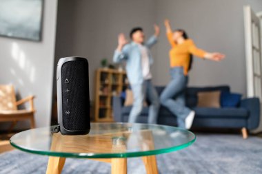 En sevdiği müzik. Tanınmayan Asyalı çift, Song Via Wireless Smart Speaker dinleyerek Modern Ev İçi 'nde eğleniyor, zıplıyor ve dans ediyor. Seçici Odaklanma Müzikal Sütun
