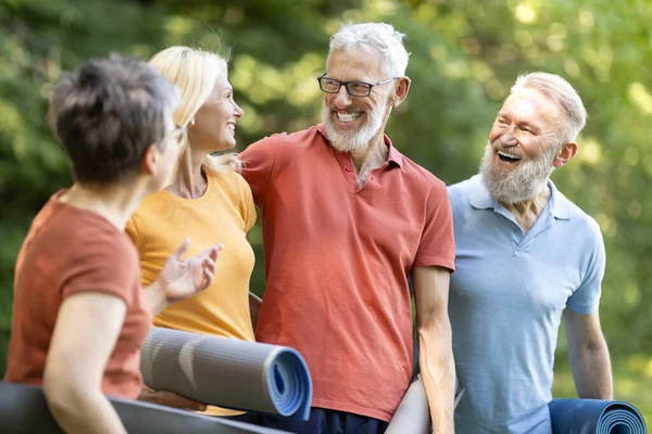 Happy Group Of Seniors Chatting Before Sport Training Outdoors, Cheerful Elderly Men And Women Holding Fitness Mats In Hands, Talking And Laughing, Mature Friends Enjoying Outside Workout, Closeup